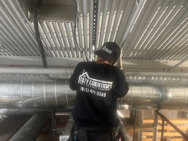 Cozy Conditions technician working on commercial ductwork